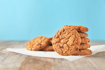 Delicious oatmeal cookies with chocolate chips on wooden table against color background