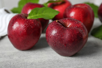 Ripe red apples with green leaves on table, closeup