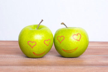 Apples in love on the wooden table.