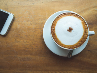 Coffee Time. Cappuccino with smartphone. on Wooden table in coffee shop. Cup of coffee in coffee shop. Empty cup of coffee.