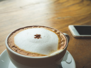 Coffee Time. Cappuccino with smartphone. on Wooden table in coffee shop. Cup of coffee in coffee shop. Empty cup of coffee.