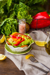 bowl of fresh salad with vegetables and greens on wooden table