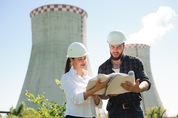 two engineers standing at electricity station, discussing plan