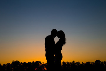 The guy and the girl at sunset, silhouette