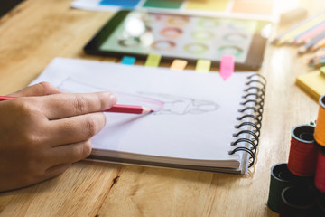 Close up of dressmaker or designer's hand working as fashion designers and drawing sketches for clothes profession and job occupation, Fashion Designer Stylish Concept