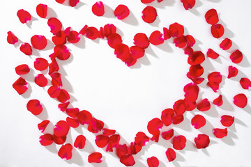Heart of red rose petals on white background.