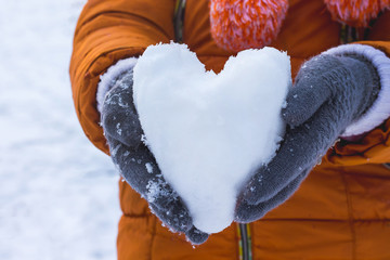 girl holding a heart of snow, wishes to congratulate her friend on Valentine's Day and wish her happiness and love