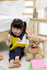 Happy asian child little girl playing with her teddy bear, family concept at home