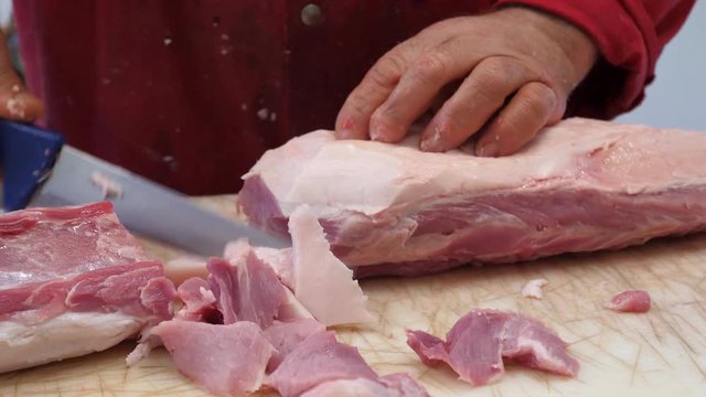 Butcher cuts pork meat in a slaughterhouse, close-up