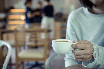 Asian woman relaxing on couch with coffee at the cafe interior - vintage style effect picture