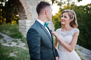 Bride and groom smiling and having great time in the forest next to the old brick bridge.