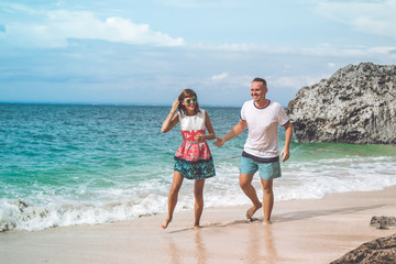Happy young honeymoon couple having fun on the beach. Ocean, tropical vacation on Bali island, Indonesia.