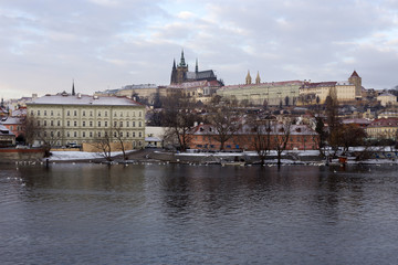 Snowy Prague Lesser Town with gothic Castle above River Vltava, Czech republic