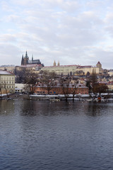 Snowy Prague Lesser Town with gothic Castle above River Vltava, Czech republic