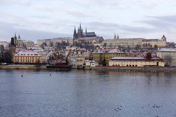 Snowy Prague Lesser Town with gothic Castle above River Vltava, Czech republic