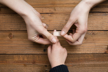 子供の手に絆創膏を貼る母の手