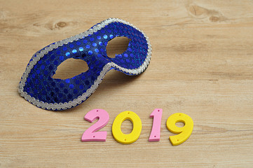 A blue masquerade mask with 2019 in colorful numbers
