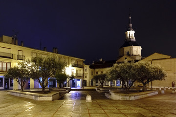 Irish Square in Alcala de Henares (Spain) on a cold and rainy night, without people and the wet ground and reflecting light from the streetlamps