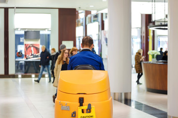 Cleaner in blue uniform on a sweeper in a shopping center
