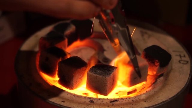 Burning coal for hookah on a special professional stove. Top view video.