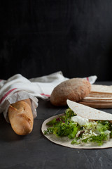 vegetarian lavash with fresh herbs and bread on a dark background