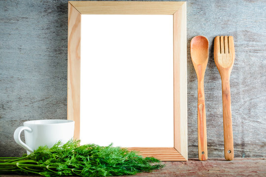 empty wooden frame with isolated white background and kitchen utensils and green dill on a wooden background