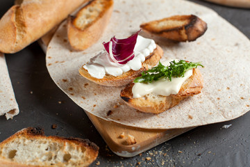 sandwiches with fresh herbs, sour cream and cheese and bread on a dark background