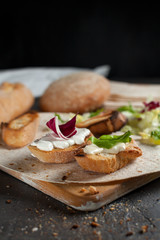 sandwiches with fresh herbs, sour cream and cheese and bread on a dark background
