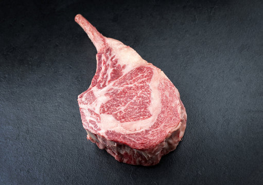 Rohes dry aged Wagyu Tomahawk Steak als close-up auf schwarzen Board