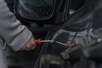 A woman holds a screwdriver in her hand and wants to scratch the car paint. She retaliates from jealousy. Concept: vandalism and crime - Powered by Adobe