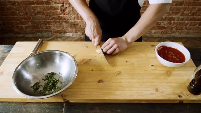 Chef cutting clove of garlic into small pieces for making pizza sauce. 4K