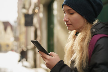 portrait of teen girl looking at smartphone on street