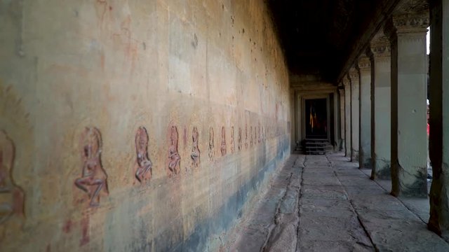 Steadicam gimbal motion down a corridor of Angkor Wat lined with bas relief apsara dancers.