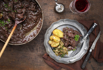 Fresh veal liver ragout in red wine sauce with fried potatoes and cabbage as top view on a plate