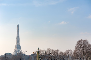 Fototapeta na wymiar Eiffel tower against blue sky in winter wit naked trees in the foreground, Paris, France