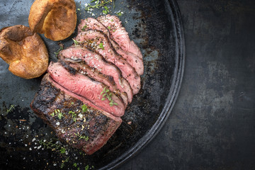 Barbecue wagyu roast beef sliced with Yorkshire pudding as top view on a tray with copy space right - obrazy, fototapety, plakaty