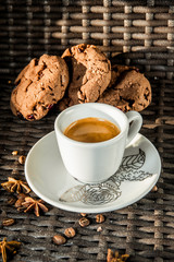 A cup of espresso on a saucer on a background with a cookie