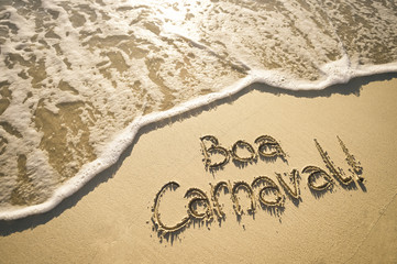 Boa Carnaval message in Portuguese (Happy Carnival in English) handwritten on smooth sand beach