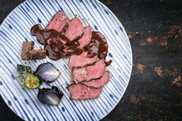 Barbecue wagyu aged fillet steak slices with brownie and chili chocolate sauce as top view on a plate