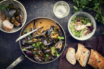 Traditional French blue mussel in bouillabaisse with lettuce and baguette as top view in a casserole