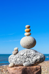 Rock zen pyramid of white stones on a background of blue sky and sea.