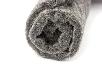 Felt close-up on a white background. Gray felt twisted into a roll on a white background.