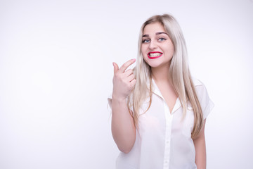 White girl with blonde hair red lipstick posing indoors isolated on a white background in white blouse showing emotion and smiling