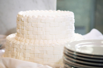 Close focus on a custom made white cake with serving plates in the foreground.  The serving plates are intentionally not in focus.