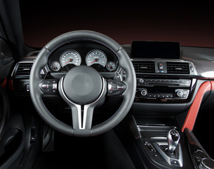 Modern luxury car Interior - steering wheel, shift lever and dashboard. Car interior luxury.Steering wheel, dashboard, speedometer, display. Red and black perforated leather.