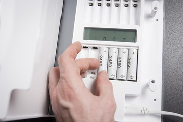 hand of person recharges rechargeable batteries close-up. Battery charging device. Charge...