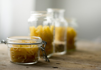 Different types of Italian pasta in a glass jars on the wooden table