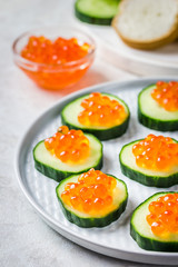 Red caviar cucumber boats on concrete background. Selective focus, space for text.