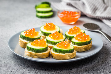 Red caviar cucumber boats on concrete background. Selective focus, space for text.