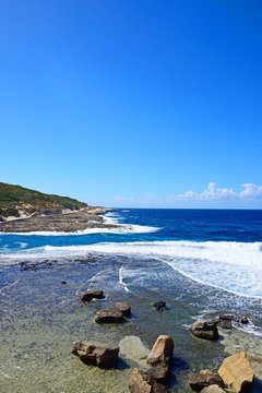 View along the coastline with rocks in shallow water in the foreground, Marsalforn, Gozo, Malta.